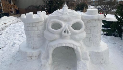 An igloo shaped like a castle with the entrance in the shape of a skull.