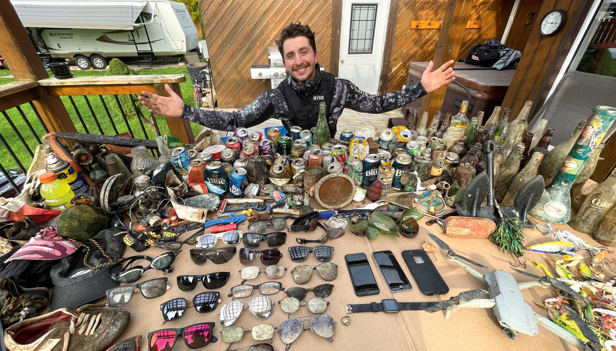 A scuba diver surrounded by items he pulled out of the lake