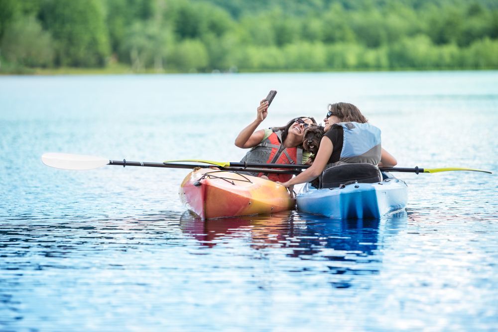 Mother and Daughter Taking Selfie with Dog in Kayaks while on family Vacation