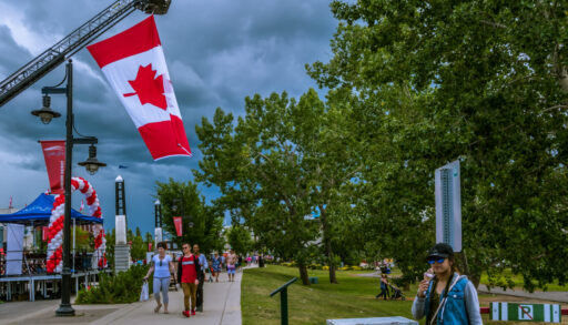 People walking along stone path under Canadian flags celebrating Canada Day
