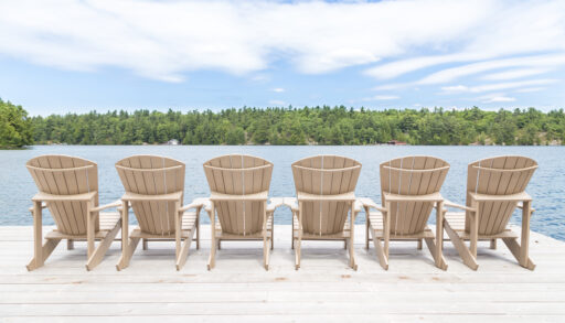 Row of Muskoka chairs on a dock looking onto the lake. short-term rental