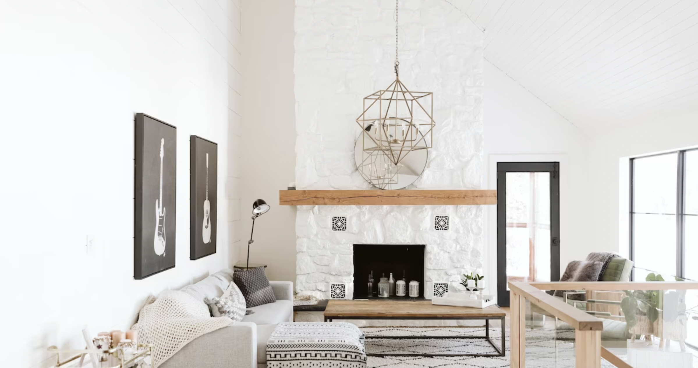 a white living room with a metal chandelier and fireplace with a wood mantle